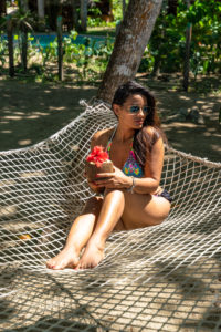Amerika, Karibik, Große Antillen, Dominikanische Republik, Cabarete, Frau sitzt in einer Hängematte im Natura Cabana Boutique Hotel & Spa und hält eine Kokusnuss in der Hand Amerika, Karibik, Große Antillen, Dominikanische Republik, Cabarete, Frau sitzt in einer Hängematte im Natura Cabana Boutique Hotel & Spa und hält eine Kokusnuss in der Hand